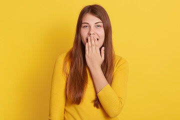 European surprised shocked astonished amazed girl covering mouth with hand, hearing unbelievable news, young beautiful woman on yellow background., emotional lady in casual attire.