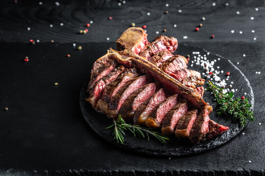 Beef T-Bone steak or aged wagyu porterhouse grilled beef steak Medium rare on a black table. American meat restaurant. menu, recipe, place for text