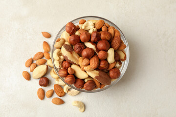 Bowl with different nuts on white textured background