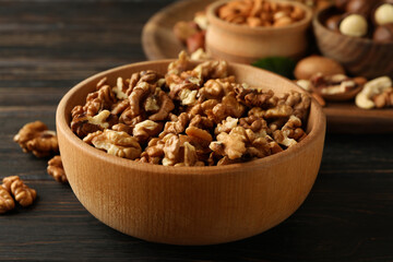 Wooden bowl with walnuts on wood background, close up