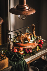 Whole roasted chicken for winter holiday festive dinner in copper roasting tin with spices, herbs and fresh fruit on concrete kitchen counter. Christmas or Thanksgiving Day cooking concept