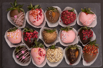 Assorted strawberries in chocolate, sweet dessert, free space for your text, sprinkled with nuts, top view, dark background.