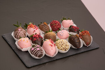 Assorted strawberries in chocolate, sweet dessert, free space for your text, sprinkled with nuts, top view, dark background.