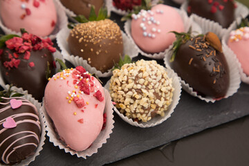 Assorted strawberries in chocolate with macaron, sweet dessert, free space for your text, sprinkled with nuts, top view, dark background.