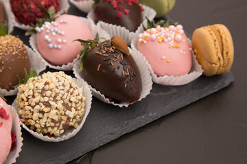 Assorted strawberries in chocolate with macaron, sweet dessert, free space for your text, sprinkled with nuts, top view, dark background.