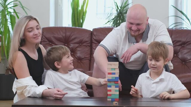 Family of four people playing in board game, wooden tower. High quality 4k footage