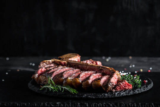 Traditional American barbecue dry aged steak sliced. porterhouse steak sliced as top view on a slate board. banner, catering menu recipe place for text