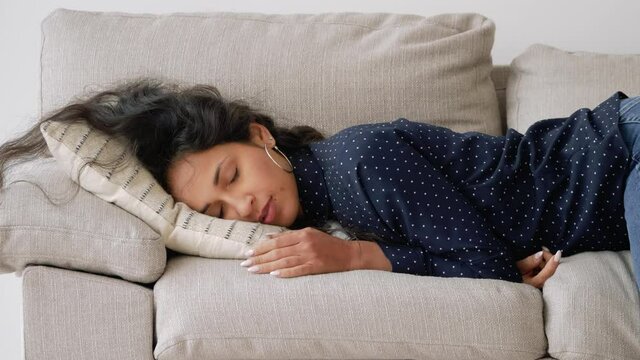 Sleepy mixed race woman falls down on sofa. Exhausted, bored, apathetic girl.
