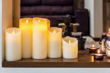 led electric and wax candles stand in the home fireplace