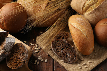 Top view of assorted rye and wheat bread, wheat and corn buns, fresh ciabatta garnished with ears.