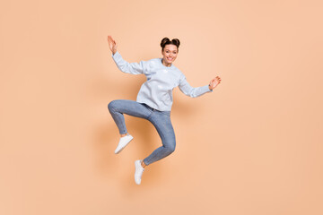 Fototapeta na wymiar Full size photo of optimistic nice brunette lady jump dance wear blue sweater jeans sneakers isolated on beige background
