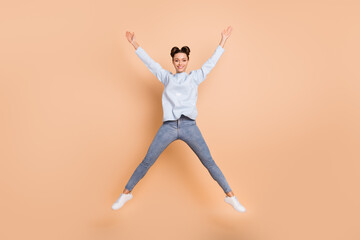 Fototapeta na wymiar Full size photo of optimistic nice brunette lady jump wear light blue sweater jeans sneakers isolated on beige color background