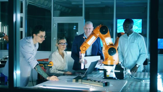 Group of scientists are talking while watching a robot