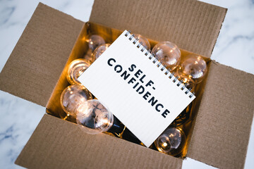  positive attitude concept, Self--confidence text on notepad surrounded by light bulbs in open box symbol of mindset