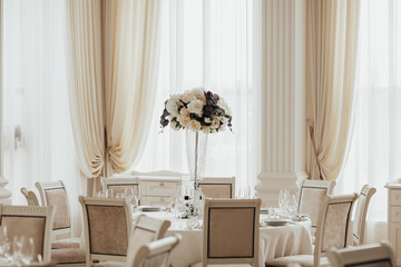 Wedding table setting decorated with fresh flowers in a vase. Banquet table for guests.