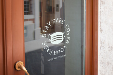 Cover your face sign on the front door of the store. The concept of fight against the virus