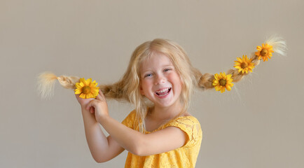 Laughing girl with yellow flowers in braids