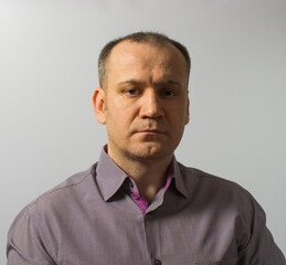 confident slightly unshaven man in gray shirt on gray background.