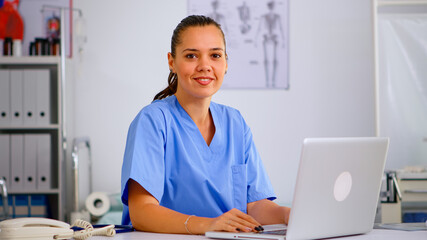 Portrait of professional medical nurse in blue practitioner uniform smiling at camera. Hospital...