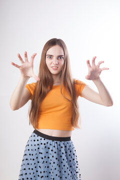 A young playful girl with long hair wants to scare someone, she growls, her grin like an animal.