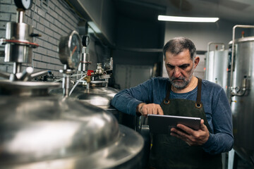 brewer working on digital tablet in his craft beer brewery