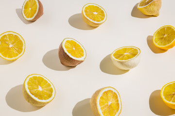 Pastel colored lemons cut in half on pastel background. Minimal summer, fruit or vegetarian concept. Flat lay.