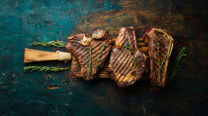 Grilled meat steaks on a wooden board: t-bone, striploin, Rib eye, new york steak. Top view. Rustic...