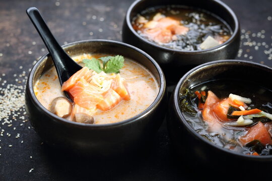 A composition of three oriental soups on a black stony background.
