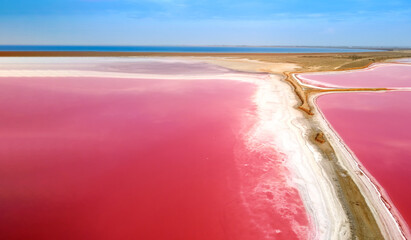 Top view of a pink lake. The narrow shore separating the lake and the sea bay. Pink lake with high...