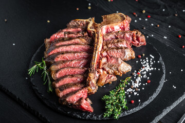grilled sliced T-bone steak with seasonings. aged wagyu porterhouse grilled beef steak Medium rare on black background. American cuisine