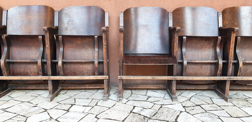 Old, brown, wooden cinema chairs put in a row. Panorama.