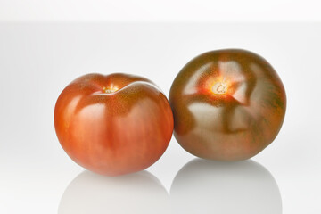Two fresh juicy tomato kumato fruits isolated on the white background.