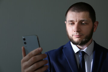 Man unlocking smartphone with facial scanner on grey background. Biometric verification