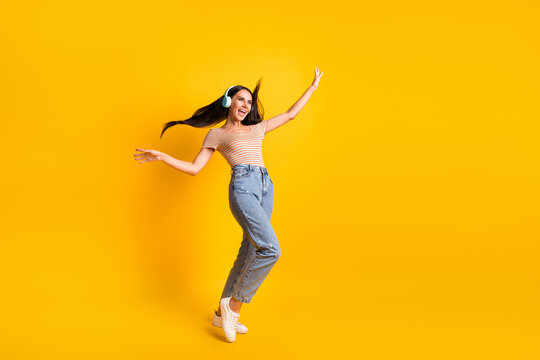 Full length body size photo of dancing girl in earphones singing smiling looking blank space isolated on bright yellow color background