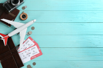 Flat lay composition with toy airplane and travel items on light blue wooden background. Space for text