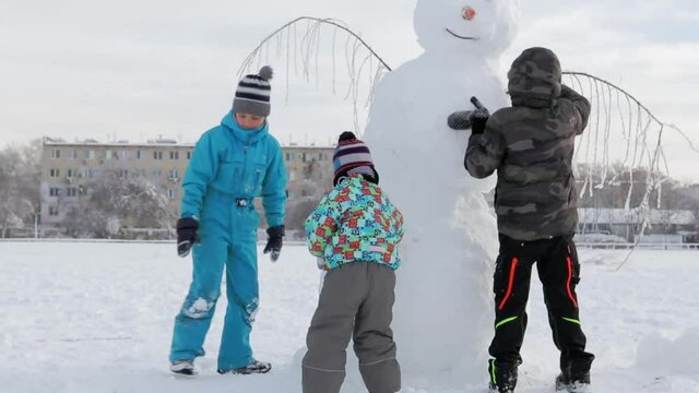 A children is shaping a snowman in heavy snow