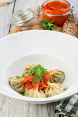 Cooked dumplings with spinach in a white plate shot from the side