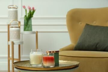 Fototapeta na wymiar Burning candles in glass holders on table indoors, space for text. Interior elements
