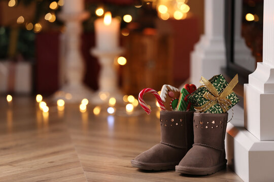 Boots filled with sweets and gift on floor in room, space for text. Saint Nicholas Day