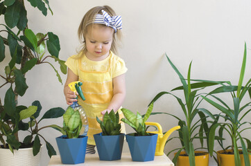 Funny little girl gardener with plants in the room at home.  Child watering and caring for indoor plants. Transplants flowers. Home gardening concept. Earth Day. Little helper by chores.