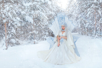 Young girl snow queen in the forest. The crown of the snow queen, the throne of ice. The queen's puffy dress. Diadem. Fabulous snowy forest. Fantasy concept