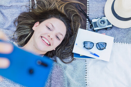 Young beautiful woman lying down taking a selfie.