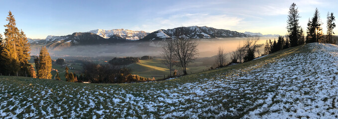 Eine malerische Landschaft, verzaubert durch den Nebel und die untergehende Sonne.