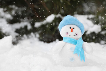 Cute small snowman toy on snow outdoors, space for text