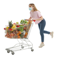 Young woman in medical mask with shopping cart full of groceries on white background