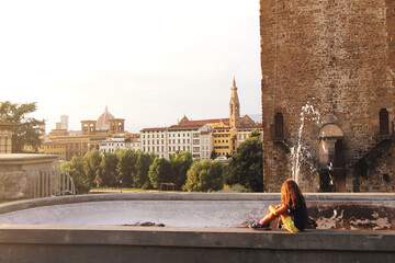Obraz premium Young girl sitting on the fountain in italian city
