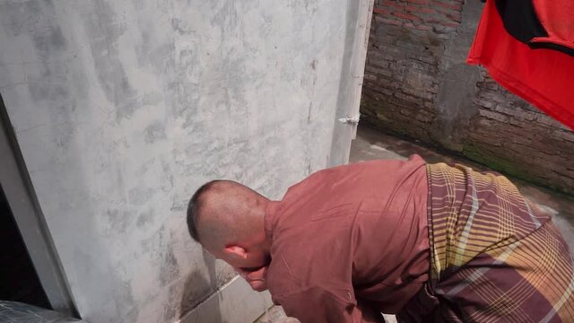 An Asian Muslim performs ablution wudhu using running water before performing prayers.