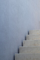 Modern concrete stairs fragment by a a gray plastered house wall with copy space