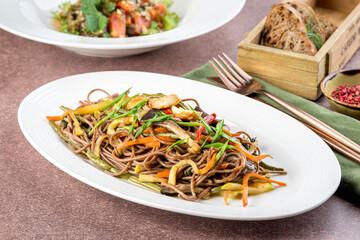 Buckwheat noodles with fresh vegetables in a white oval plate