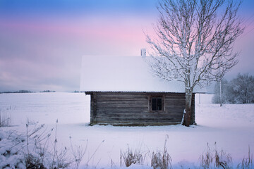 The Abandoned old log house in Latvian winter landscape.